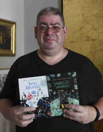 A picture of writer Ben Aaronovitch holding two of his books.